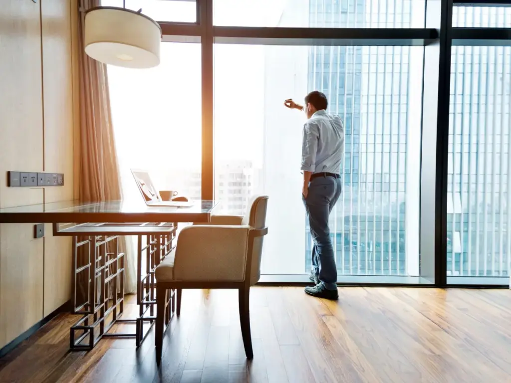 Prioritäten setzen Unternehmer. Eine Führungskraft steht allein am Fenster eines Büros und blickt nach außen – Moment der Entscheidung und Verantwortung.
