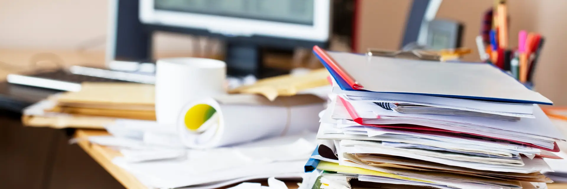 Ungestapeltes Arbeitsmaterial auf einem Schreibtisch – viele Themen ohne klare Prioritäten oder Entscheidungen.